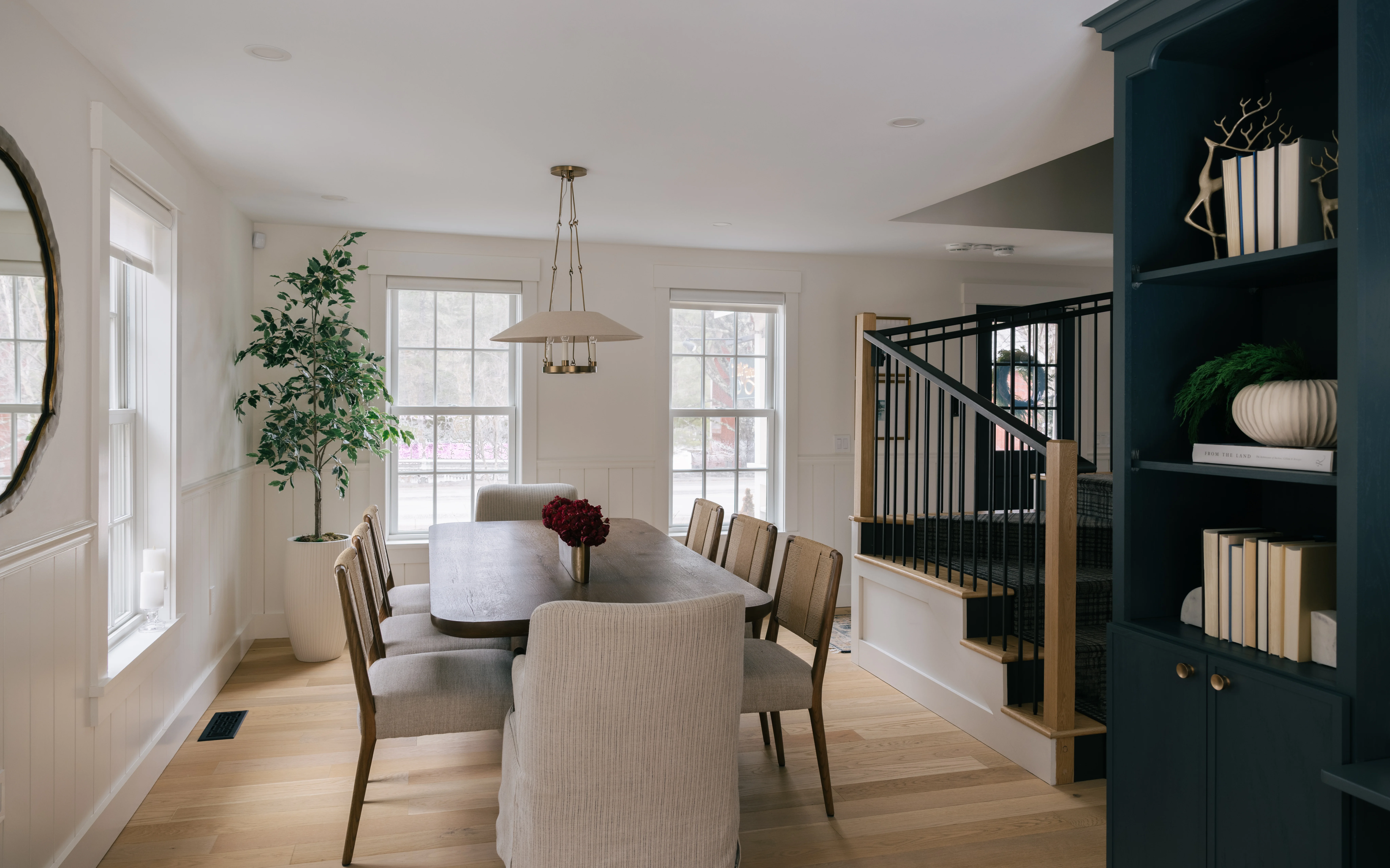 Library dining table styled with books and decorative accents beneath the built-in shelving
